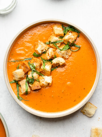 Bowl of tomato basil soup with croutons and basil.
