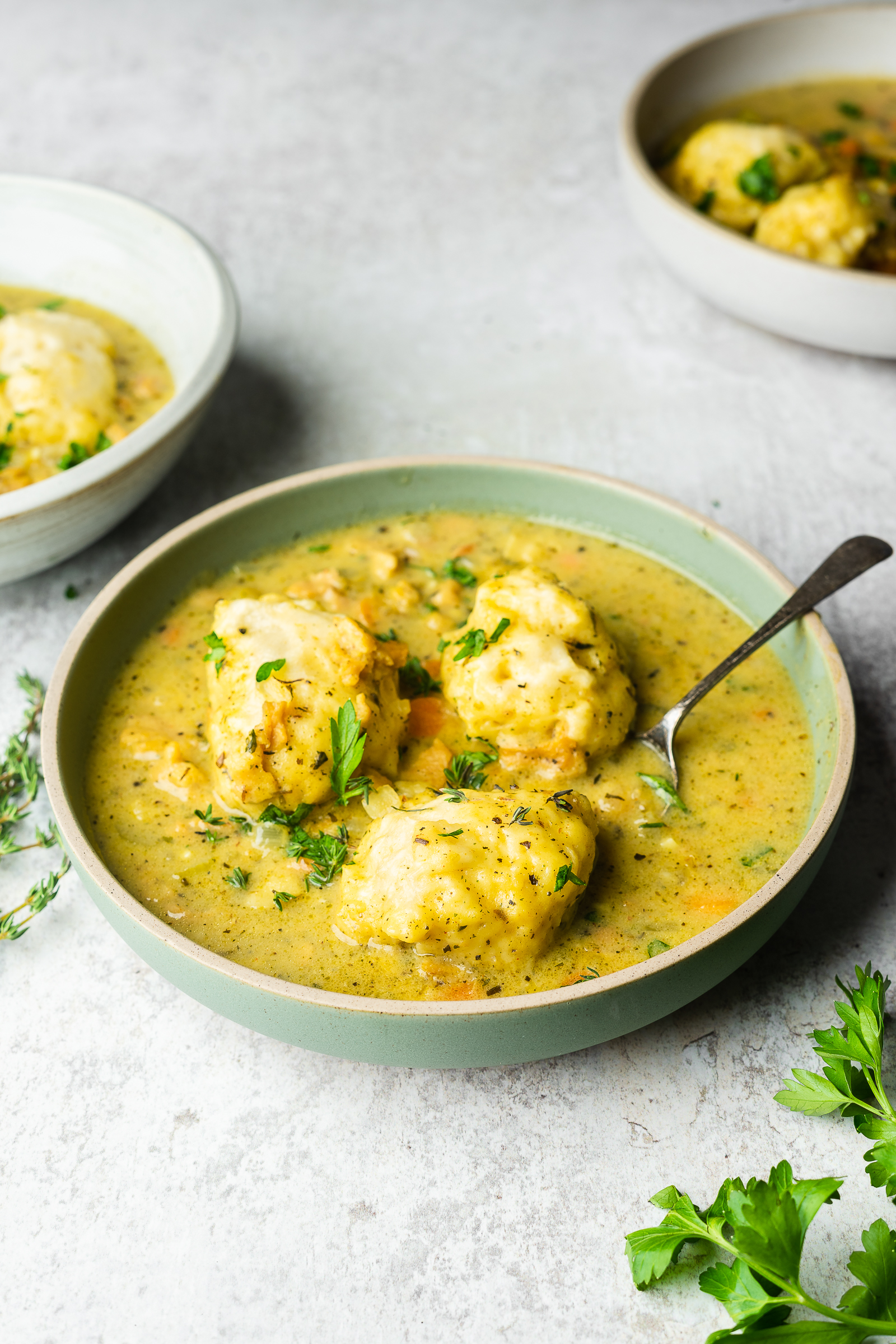 Chicken and dumplings in a green shallow serving bowl.