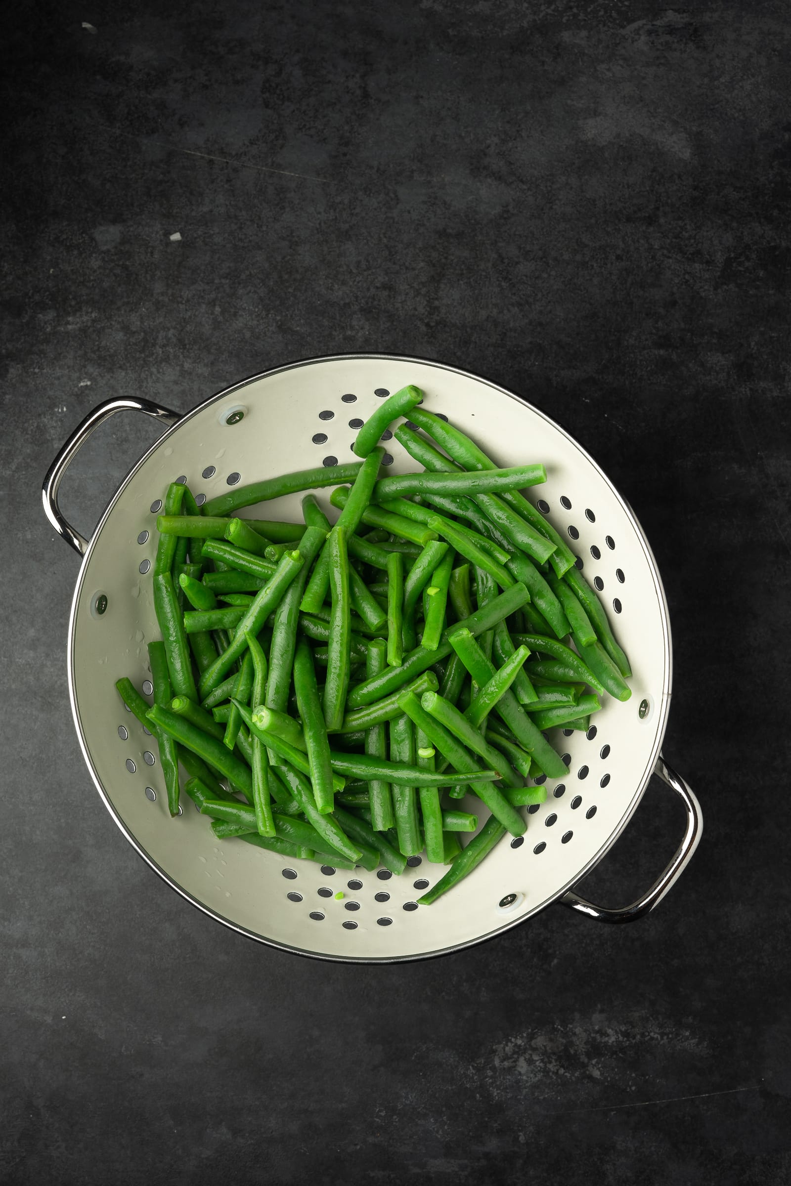Green beans in a white strainer.