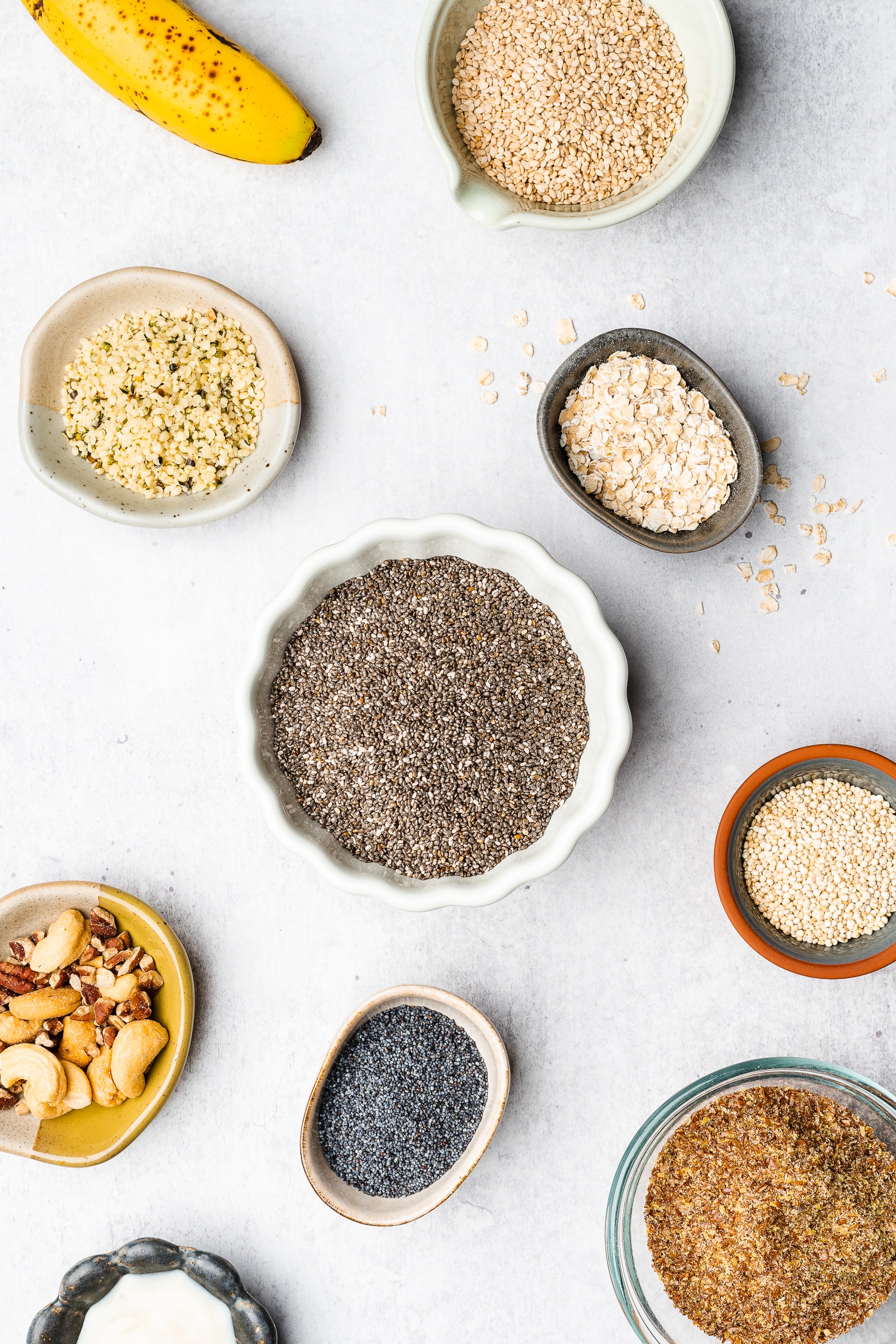 Nuts and seeds displayed in small bowls on a white/gray backdrop.