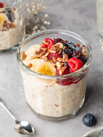 Overnight oats garnished with banana, pecans, and frozen berry blend.
