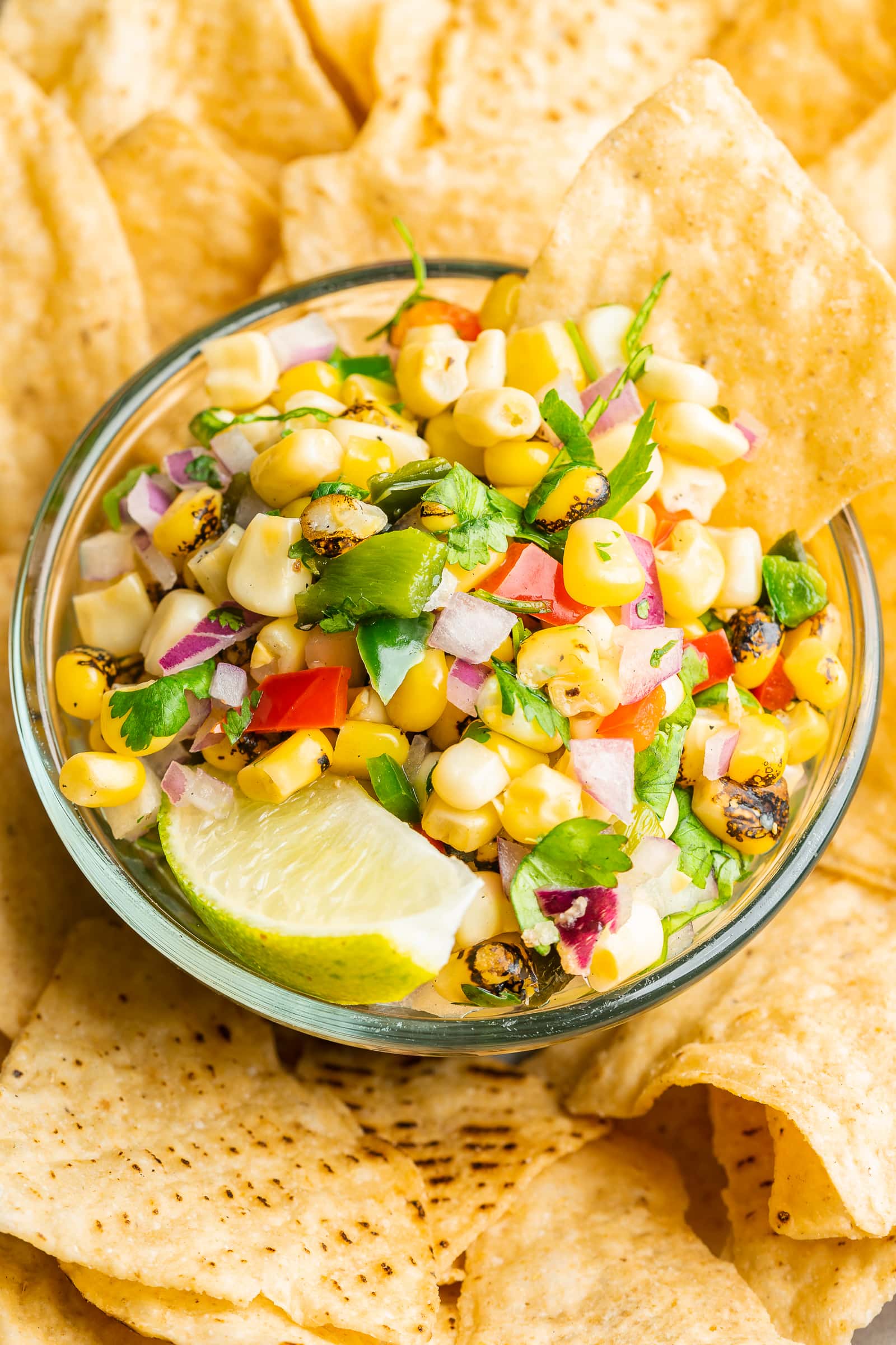 Corn salsa in a serving dish surrounded by tortilla chips.