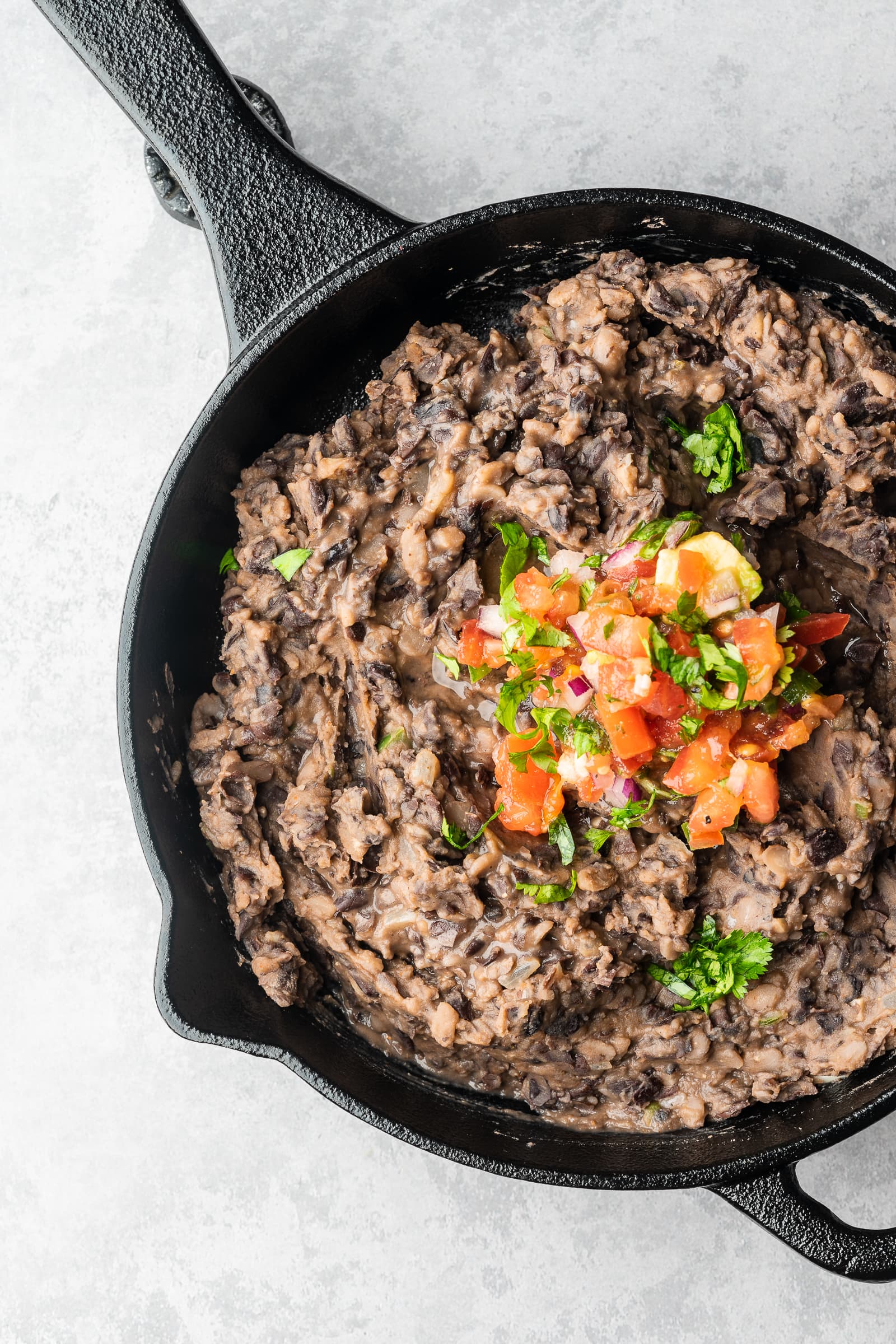 Refried black beans topped with pico.