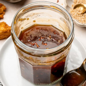 Vegan teriyaki sauce in a glass jar garnished with red pepper flakes.
