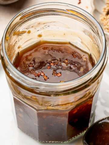 Vegan teriyaki sauce in a glass jar garnished with red pepper flakes.