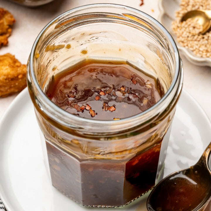 Vegan teriyaki sauce in a glass jar garnished with red pepper flakes.