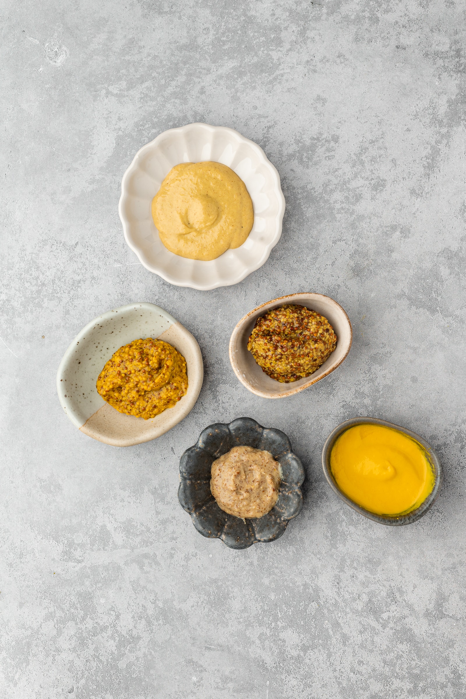 Multiple mustards in small dishes to show texture.