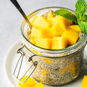 Mango chia pudding in glass jar topped with mango chunks and garnished with mint.