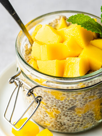 Mango chia pudding in glass jar topped with mango chunks and garnished with mint.