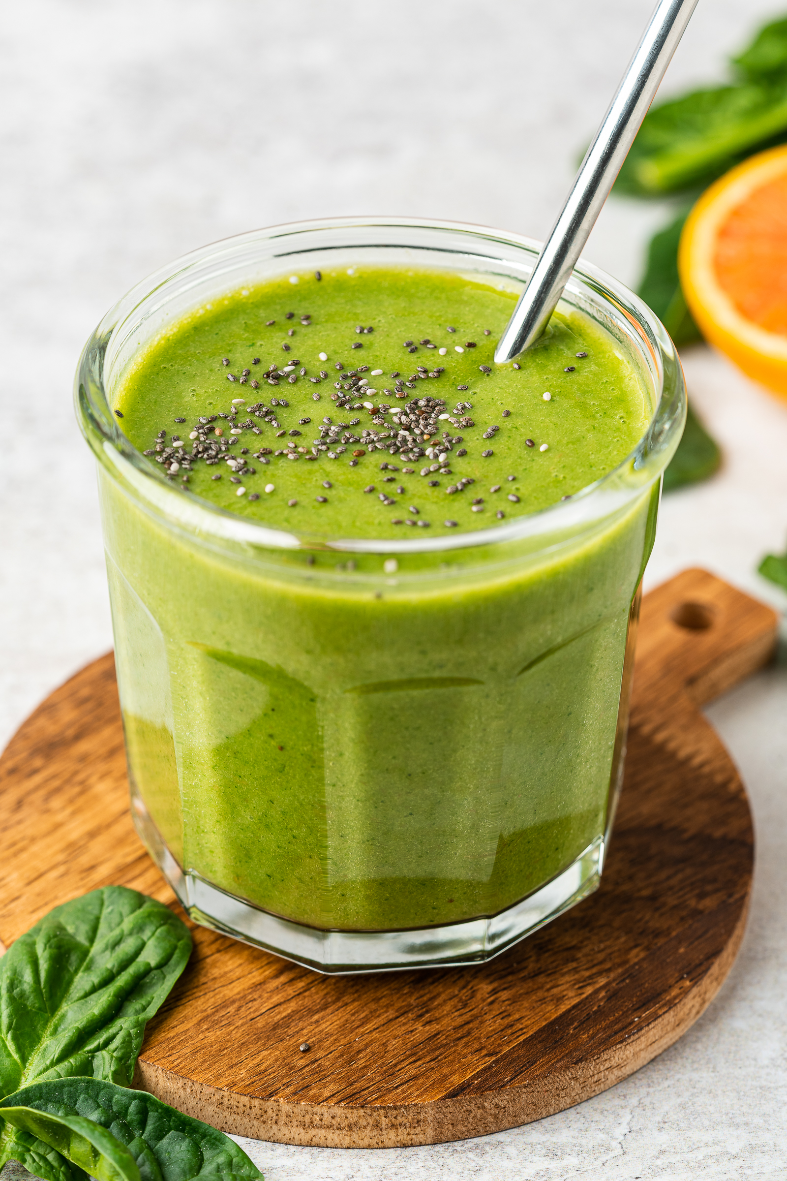 Orange spinach smoothie in a glass jar garnished with chia seeds.