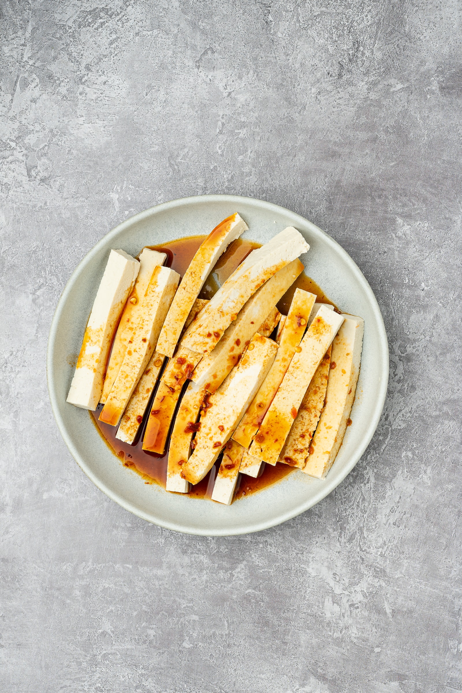 Tofu strips in a bowl with marinade.