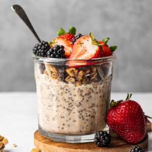 Creamy overnight oats without yogurt topping with granola, strawberries, and blackberries.