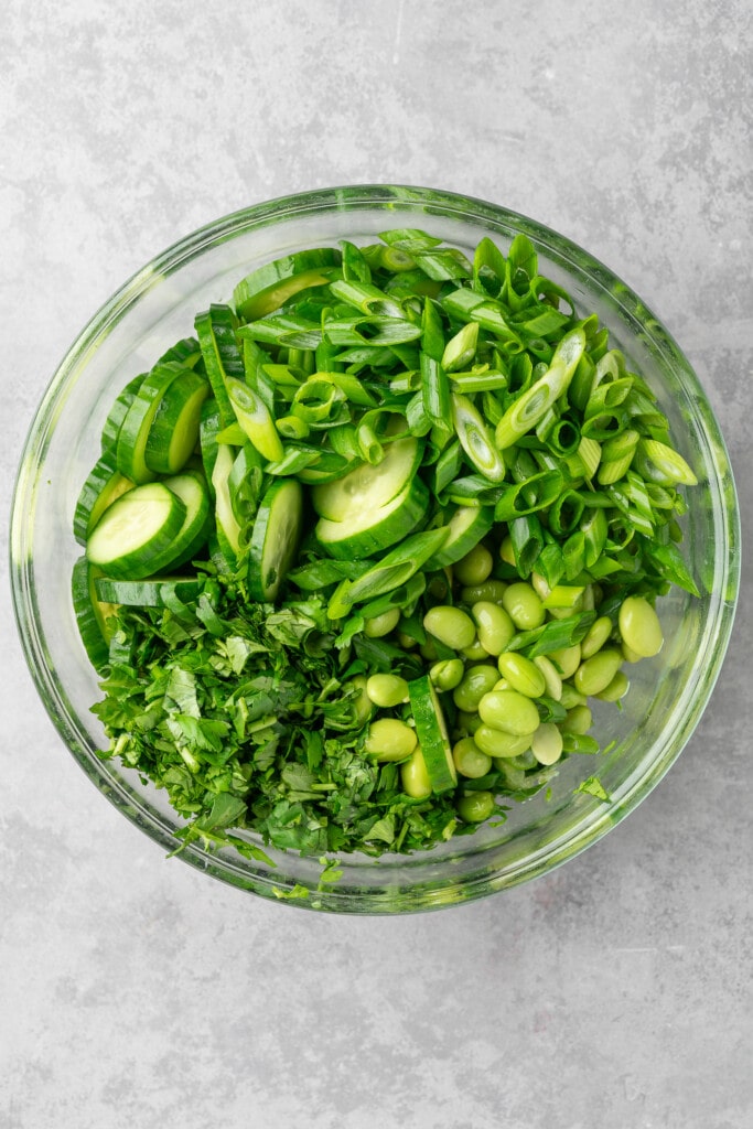 edamame, cucumber, green onion, and cilantro in a glass bowl.
