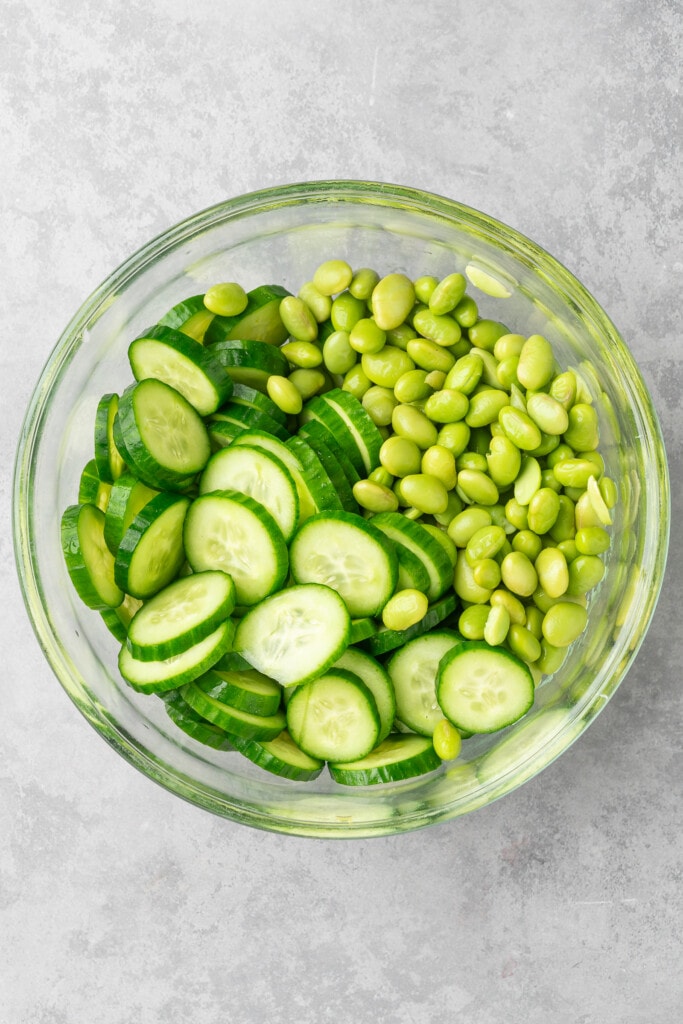 Cucumber slices and edamame in a glass bowl.