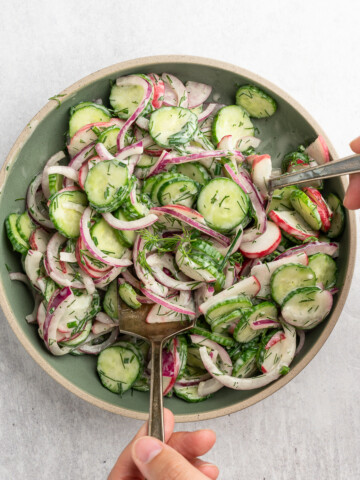 Cucumber salad being tossed together.