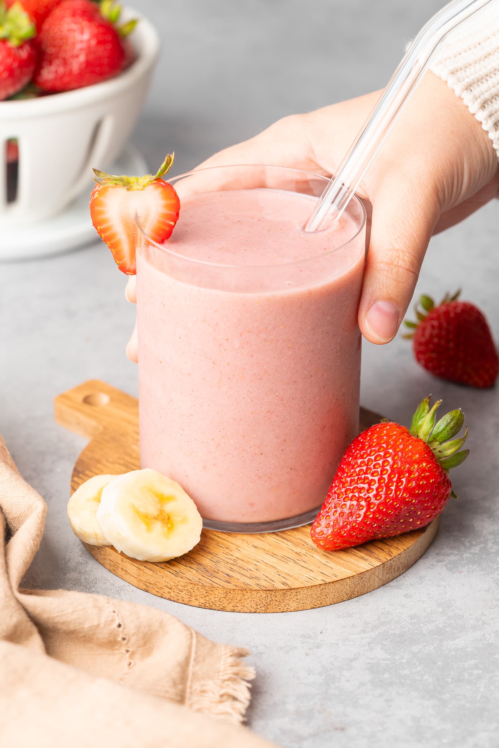 Almond milk strawberry smoothie in a glass cup garnished with strawberry slice.