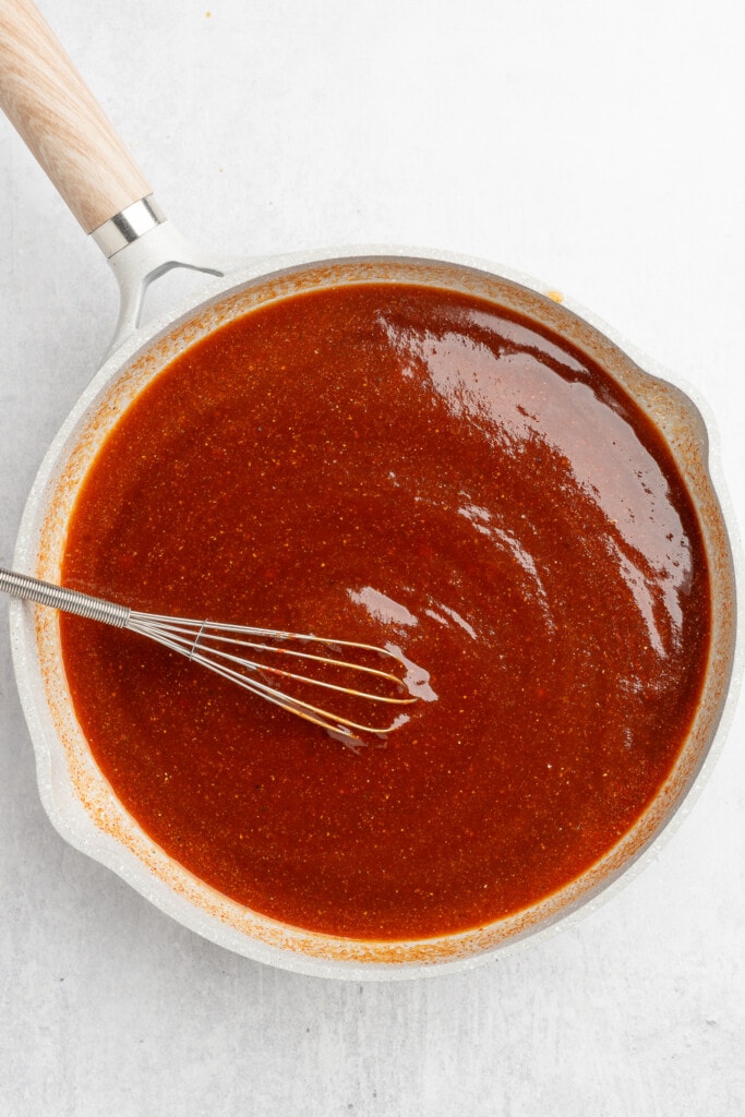 Whisking together bbq sauce ingredients in a pan.