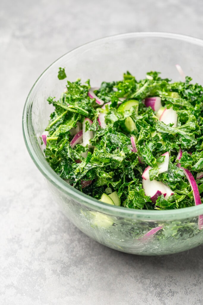 Massaged kale and vegetables in glass bowl.