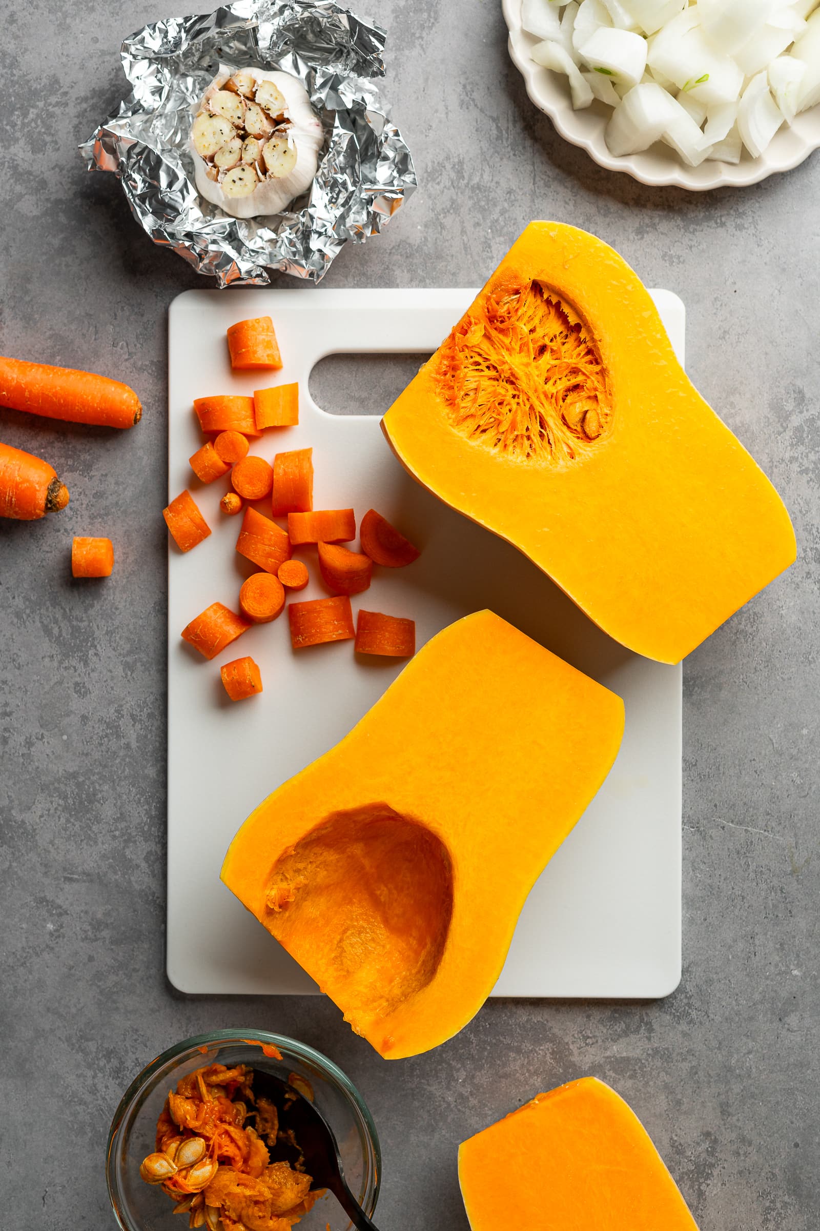 Cut carrots and butternut squash on a white cutting board.