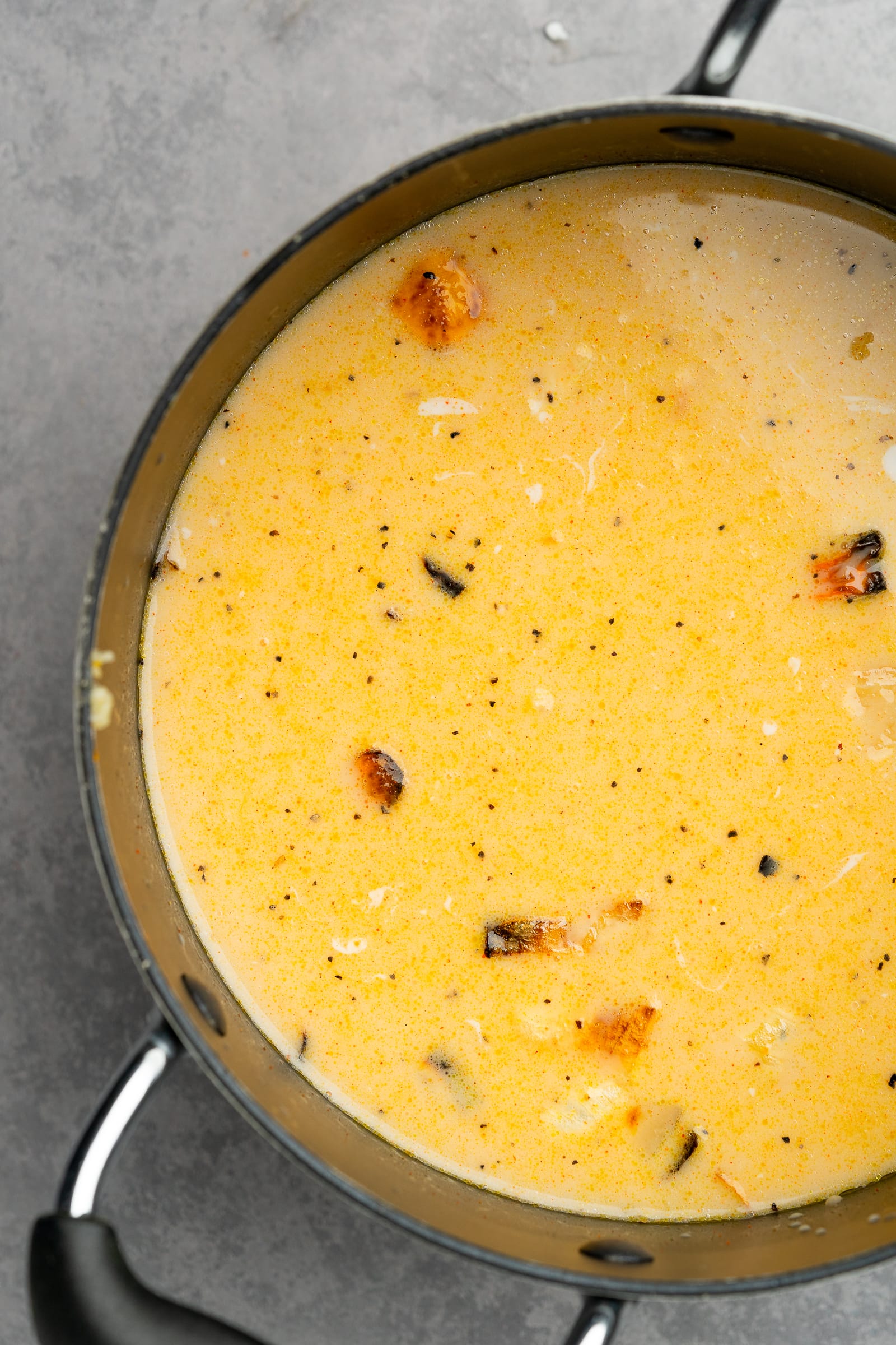 Roasted vegetables in large pot with spices, vegetable broth, and coconut milk.