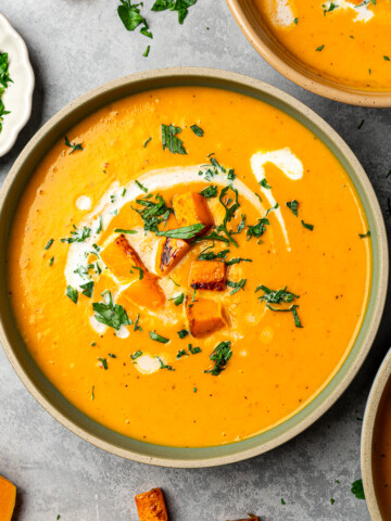 Butternut squash divided into three bowls topped with roasted squash, parsley, and coconut milk drizzle.