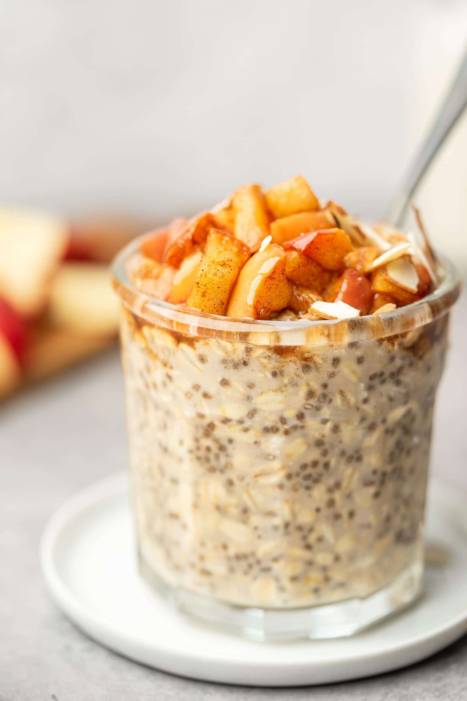 Overnight oats in a glass jar topped with cooked cinnamon apples.