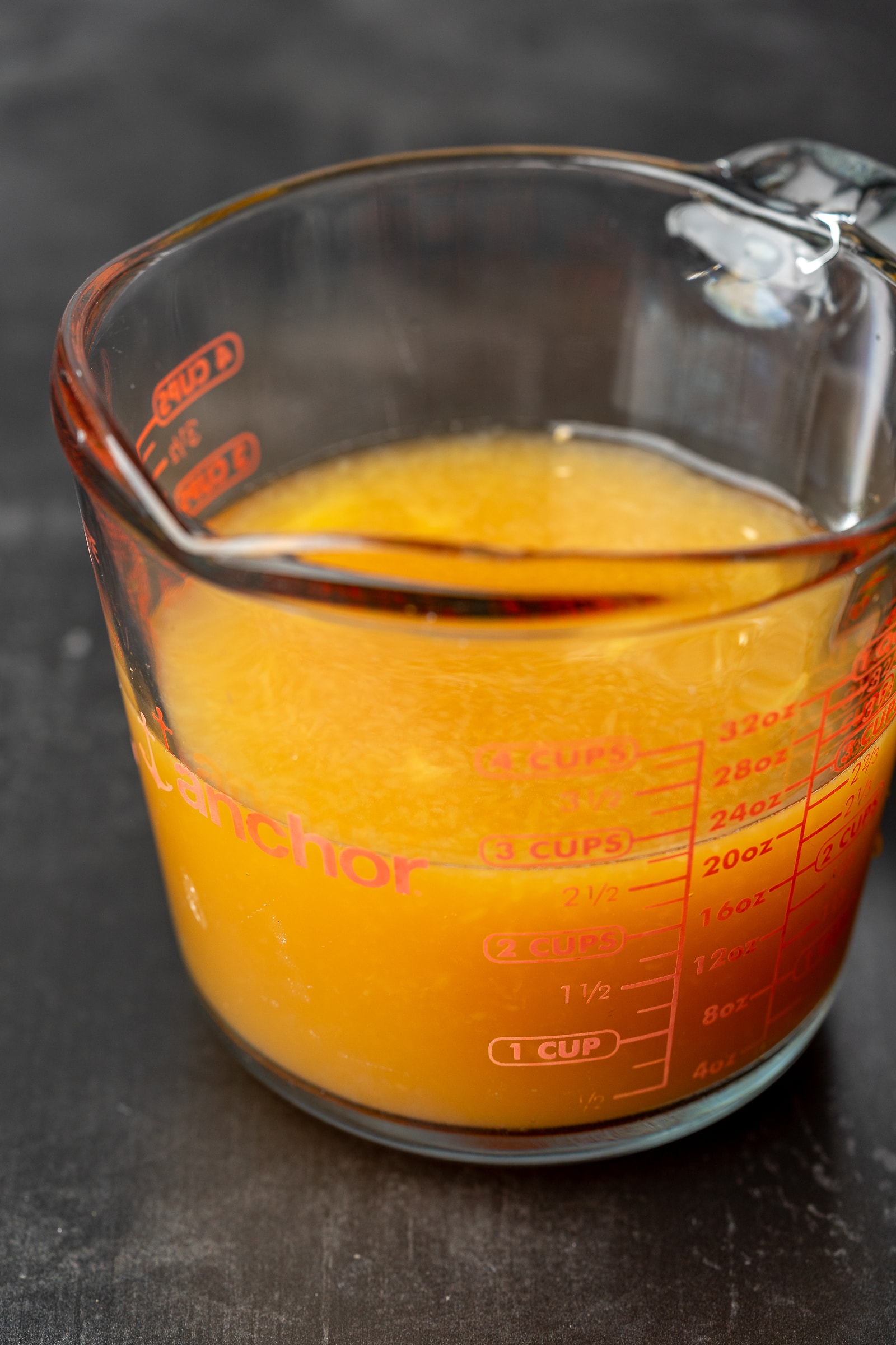 Orange juice and apple cider in a glass measuring cup.
