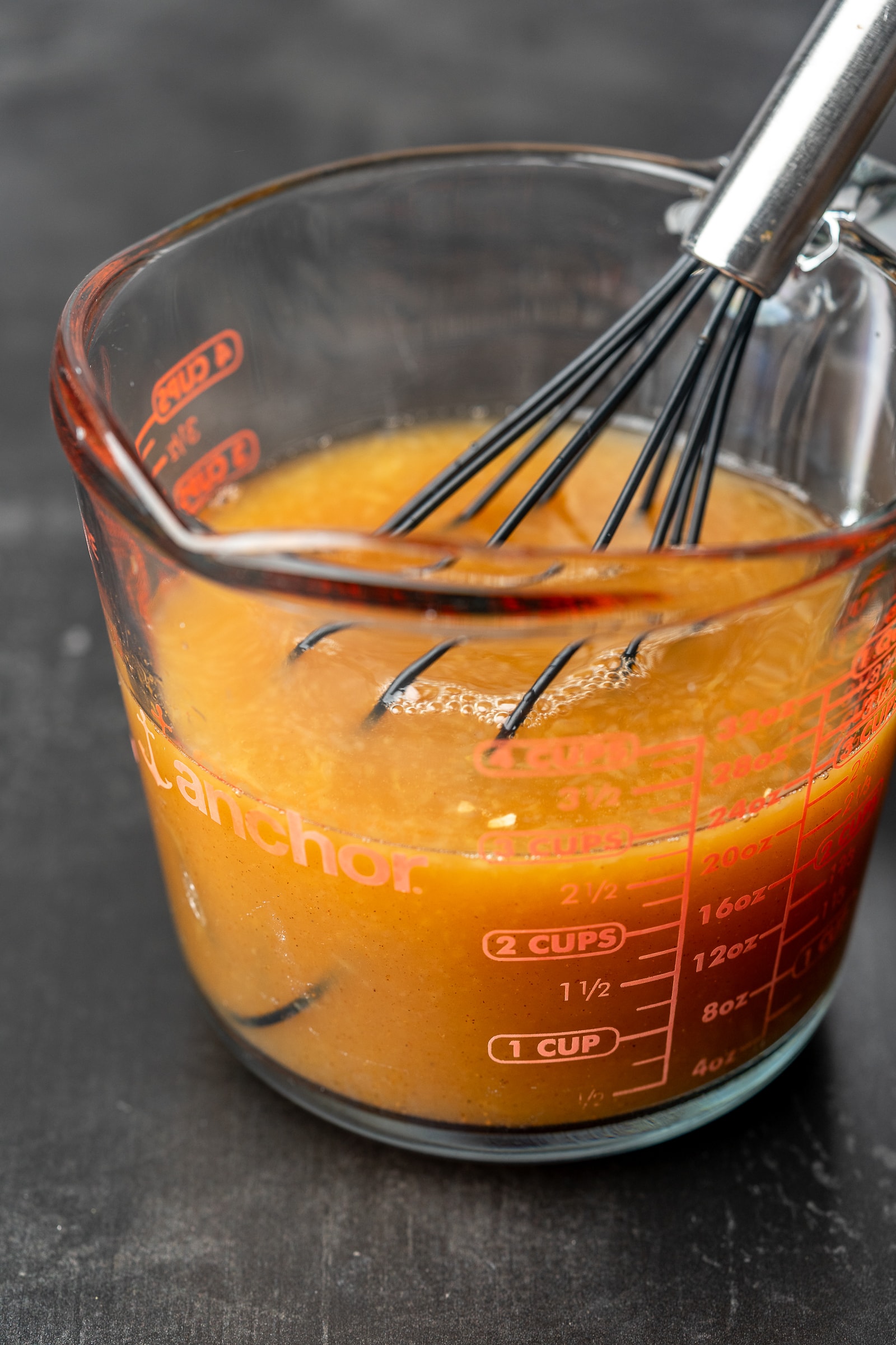 Orange juice, apple cider, and brown sugar syrup in a glass measuring cup.