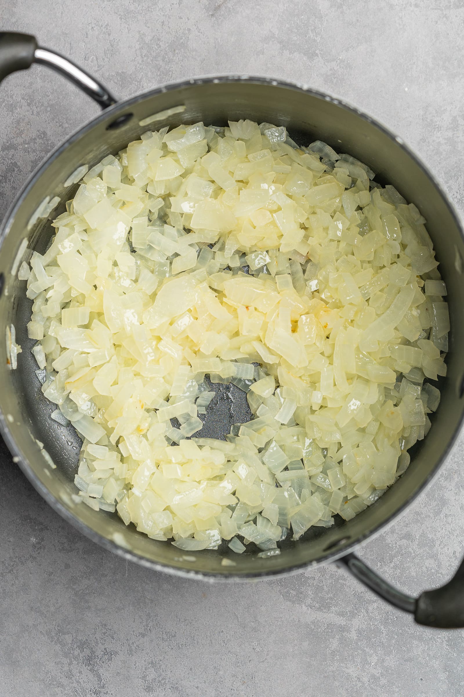 Onions in a large soup pot being sautéed.
