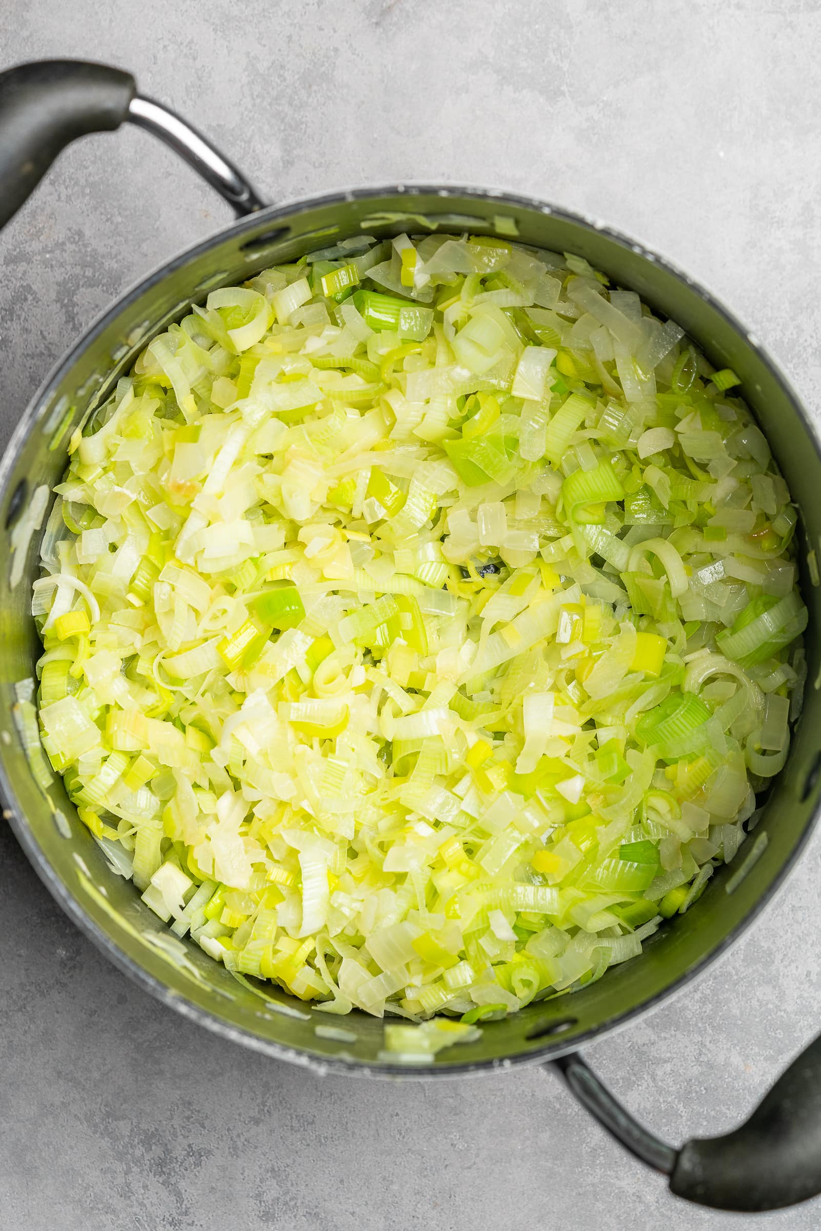 Onions and leeks being cooked in a large soup pot.