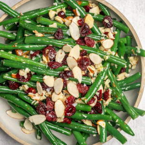Garlic green beans garnished with cranberries and almonds on a serving dish.
