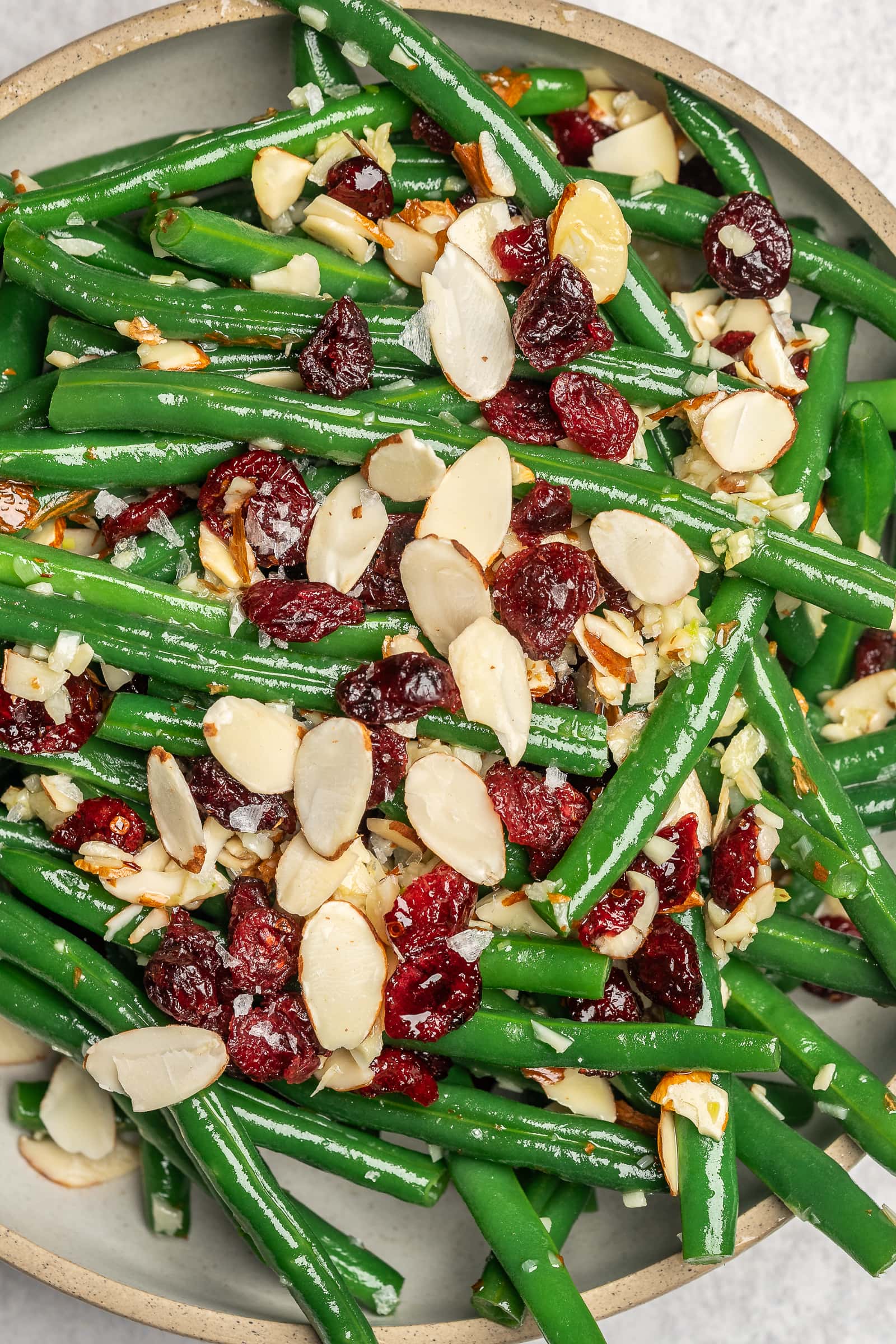 Garlic green beans garnished with cranberries and almonds on a serving dish.