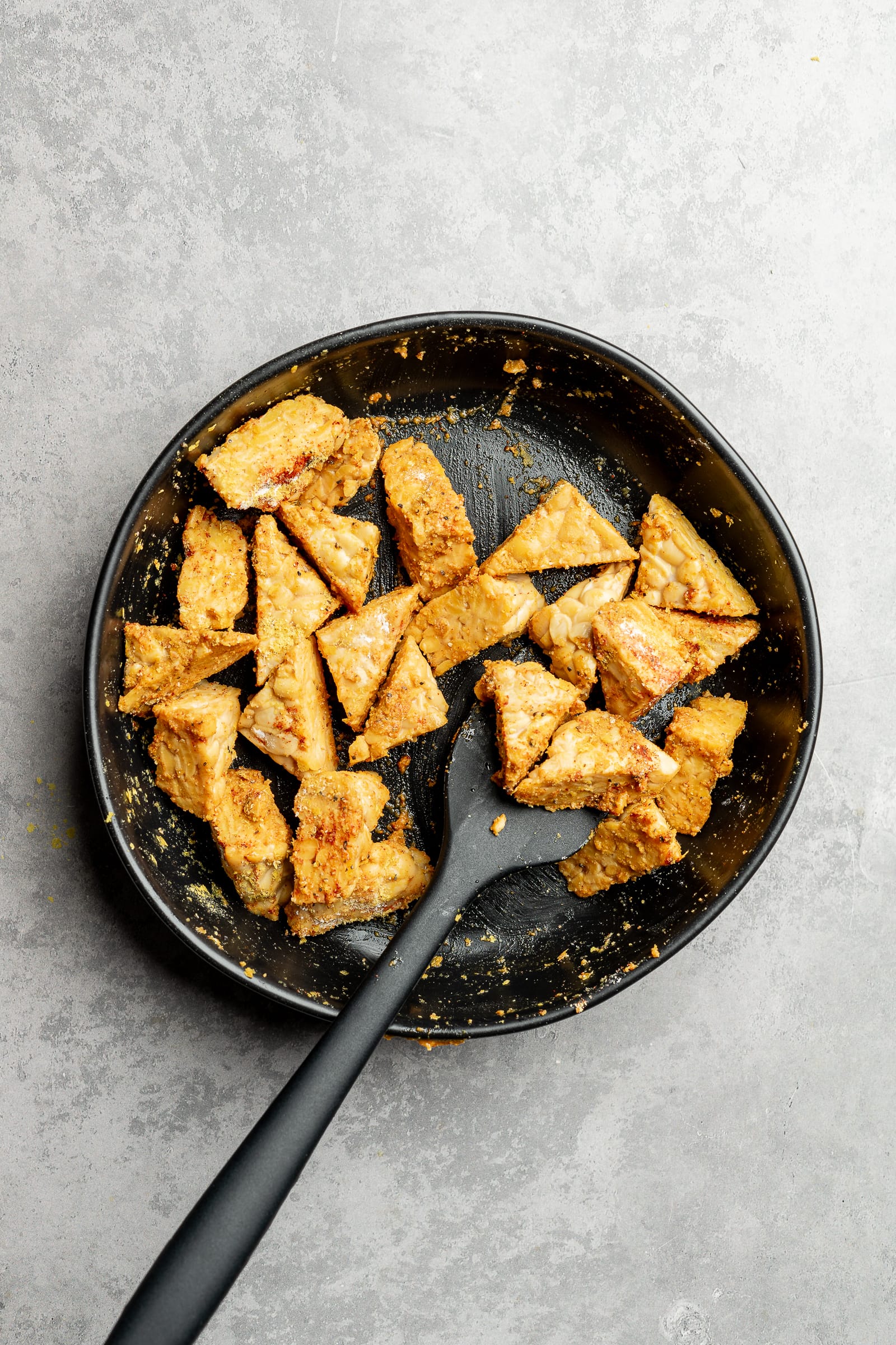 Tempeh cut in small triangles and placed in a large shallow bowl and tossed in seasonings, cornstarch, and nutritional yeast.