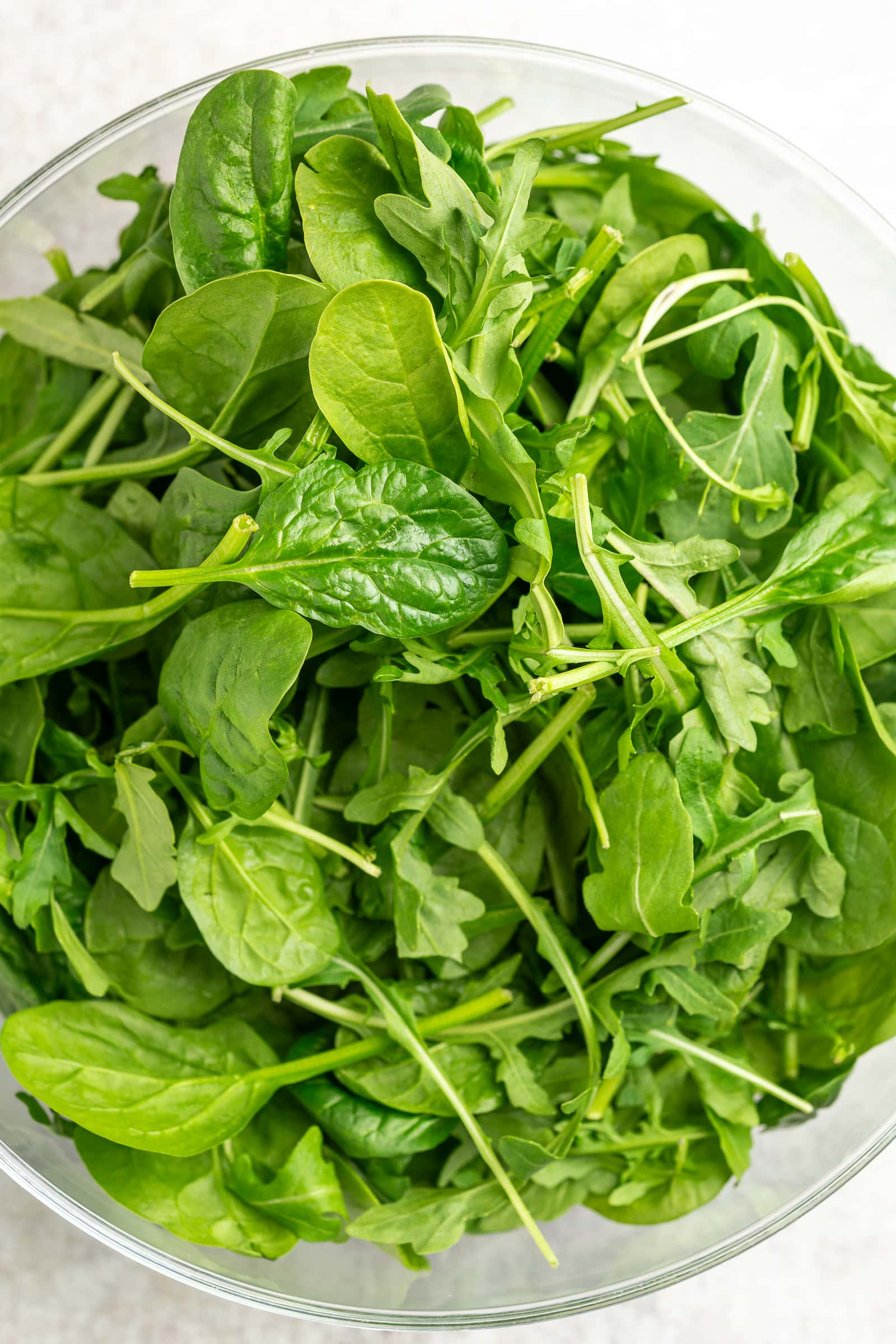 Arugula and baby spinach mixed together in a large bowl.