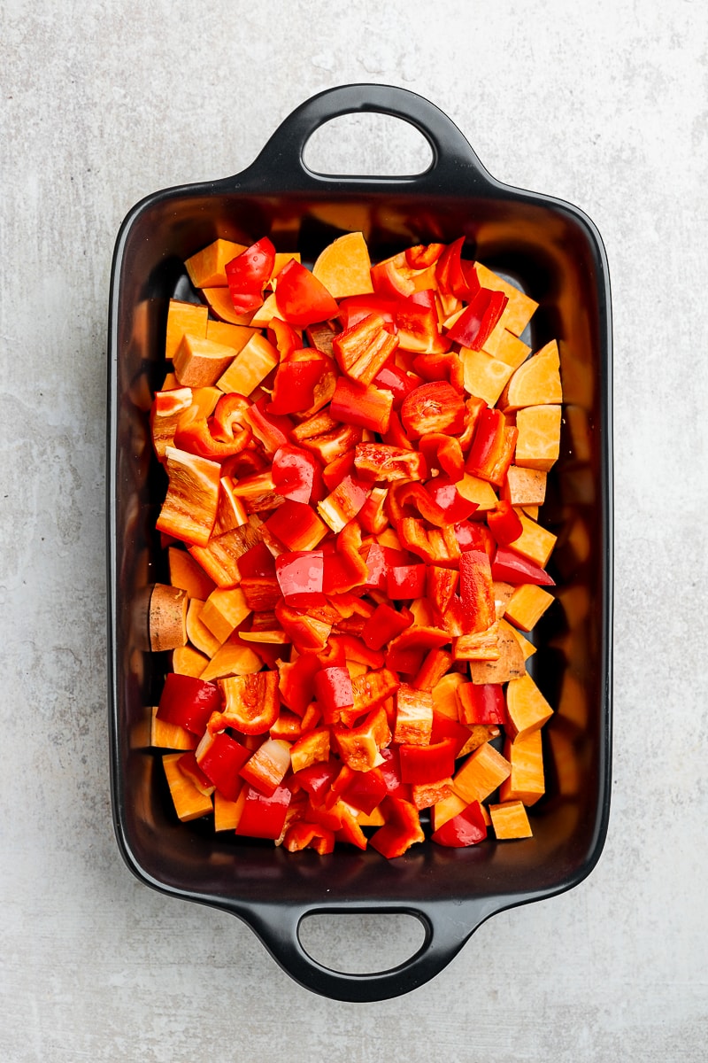 Chopped peppers and sweet potatoes in a baking dish.