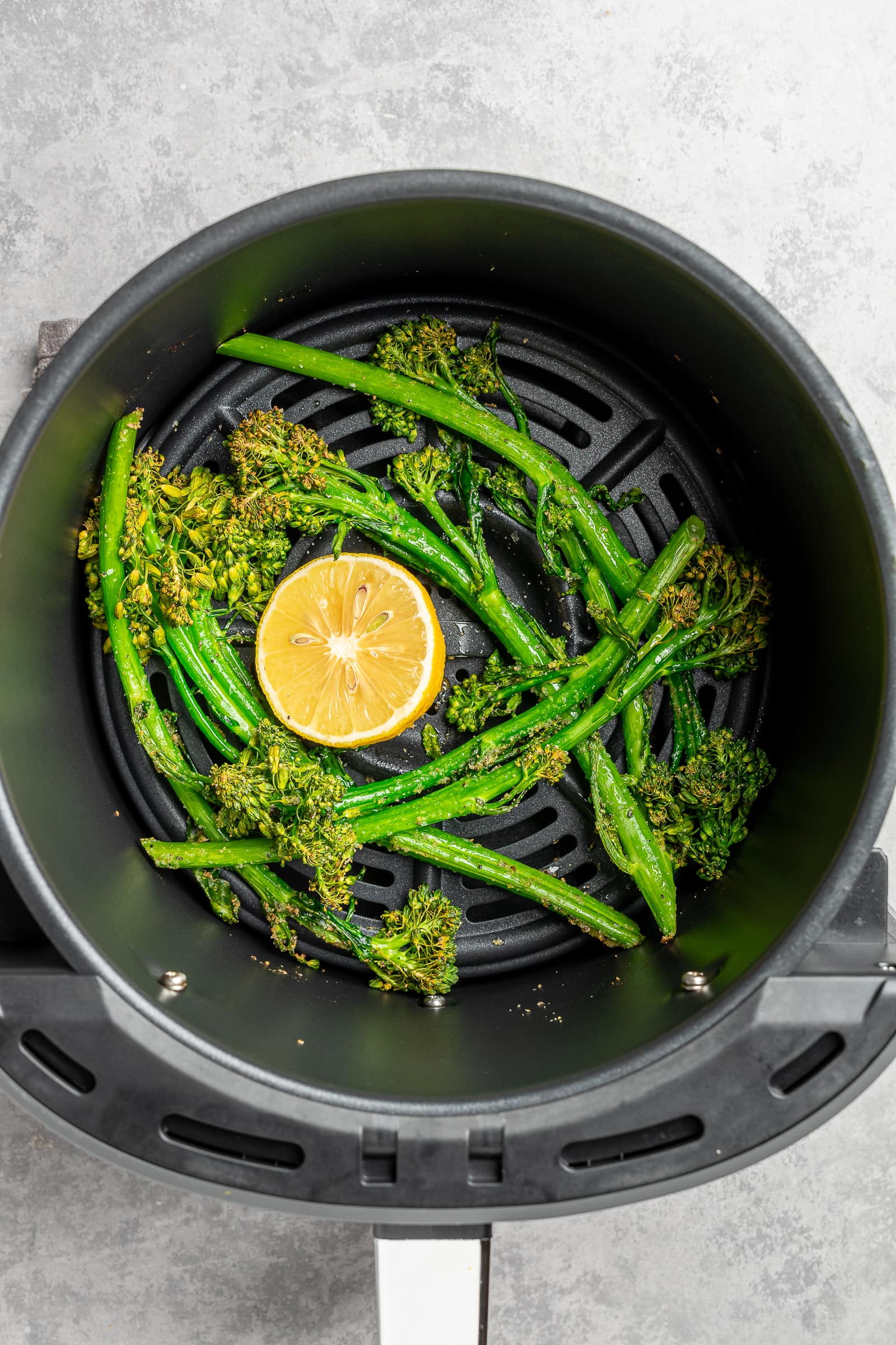 Crispy, air fried broccolini in an air fryer basket.
