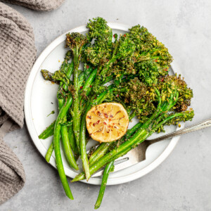 Crispy broccolini on a serving plate with lemon.