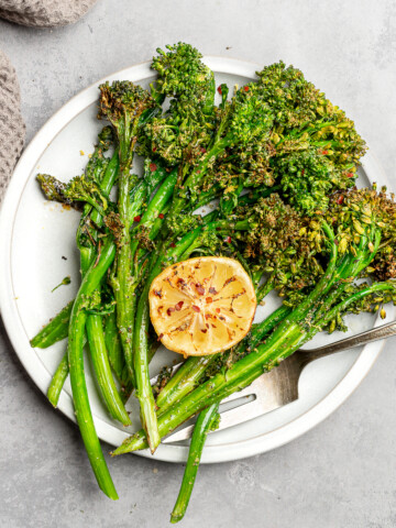 Crispy broccolini on a serving plate with lemon.
