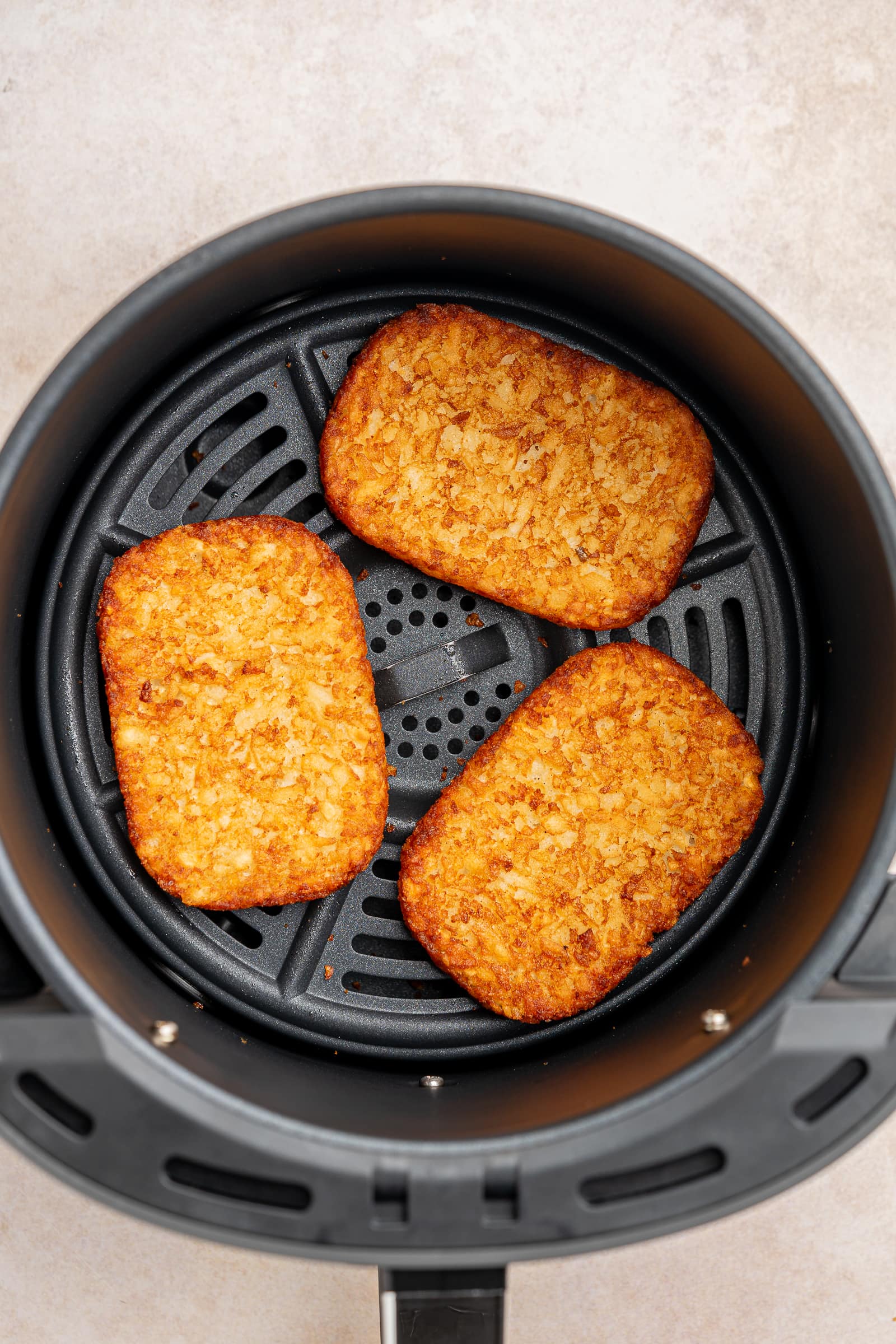 Crispy, golden air-fried hash browns in an air fryer basket.