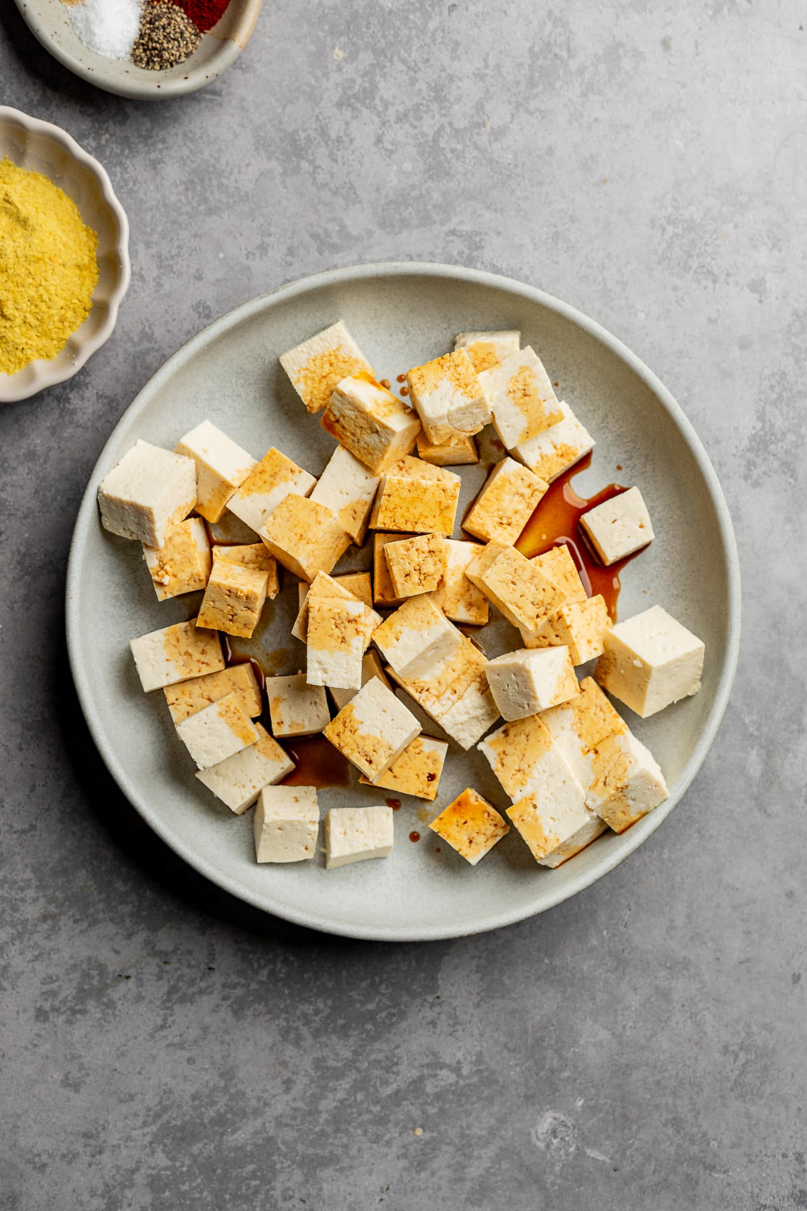 Tofu cubes in a shallow bowl with soy sauce over the top.