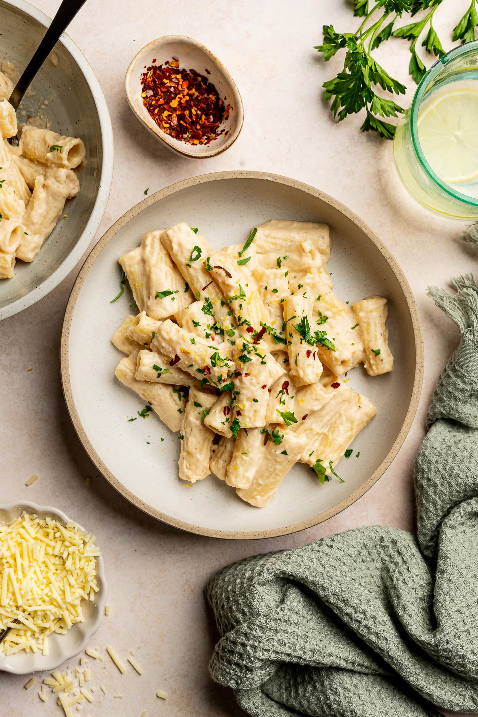 Cashew pasta garnished with red chili flakes, parsley, and lemon zest in a serving bowl.