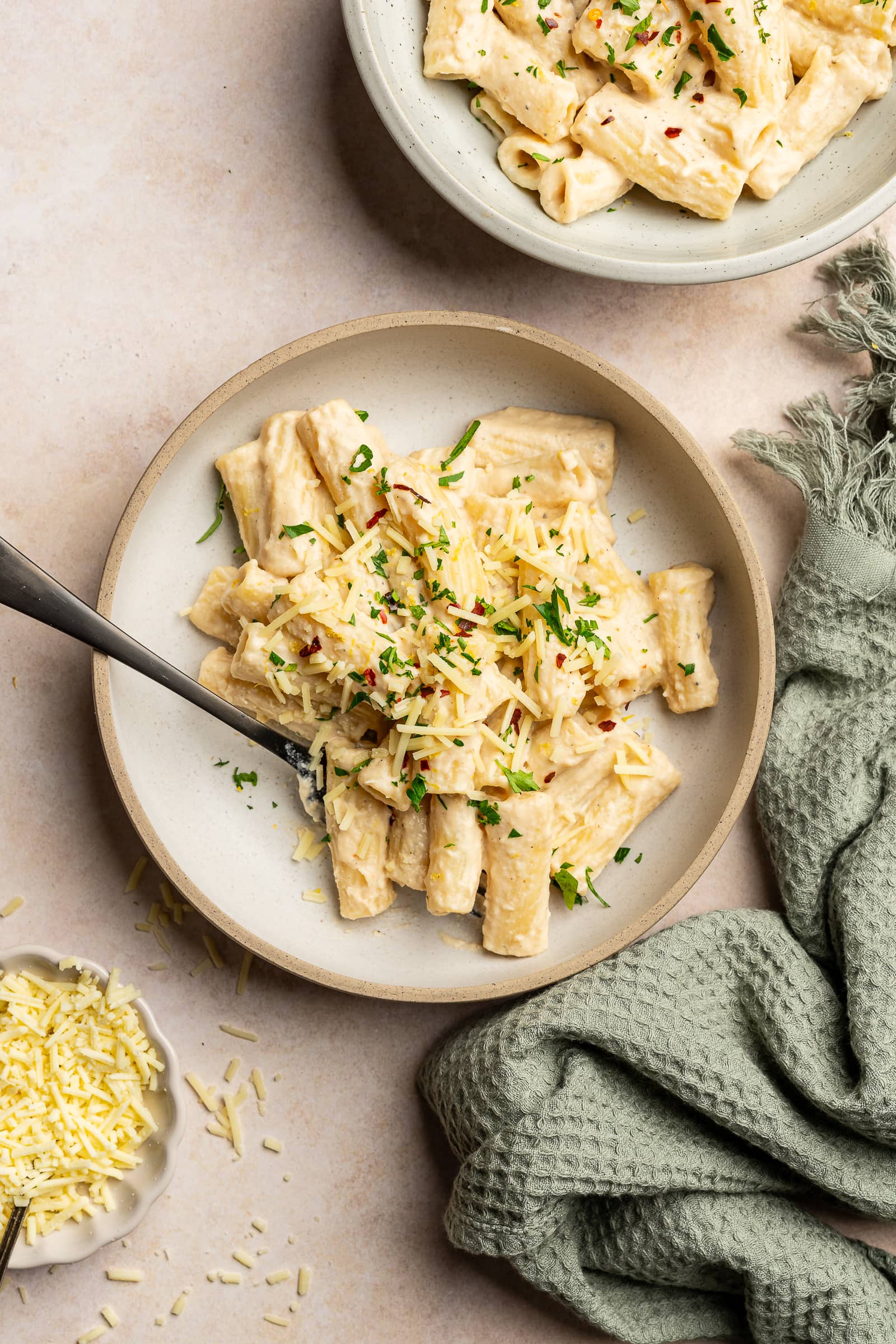 Cashew pasta garnished with red chili flakes, parsley, and lemon zest in a serving bowl.