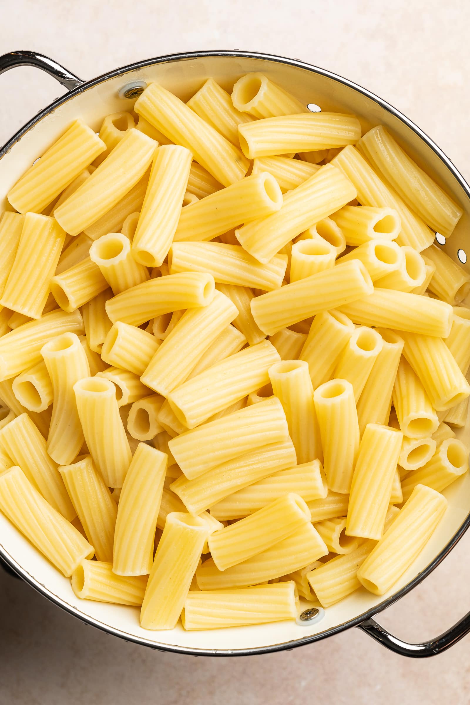 Cooked rigatoni pasta in a pasta strainer.