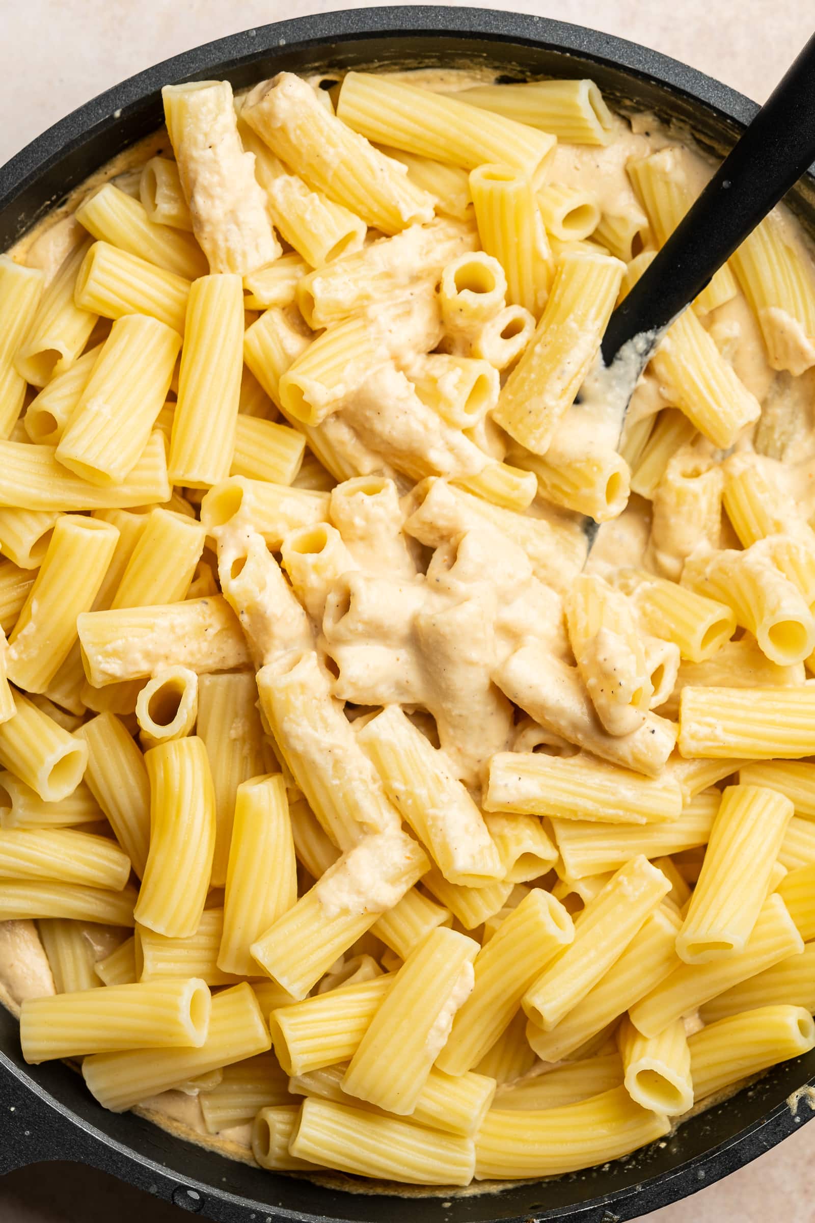 Pasta being mixed into the cashew alfredo sauce.