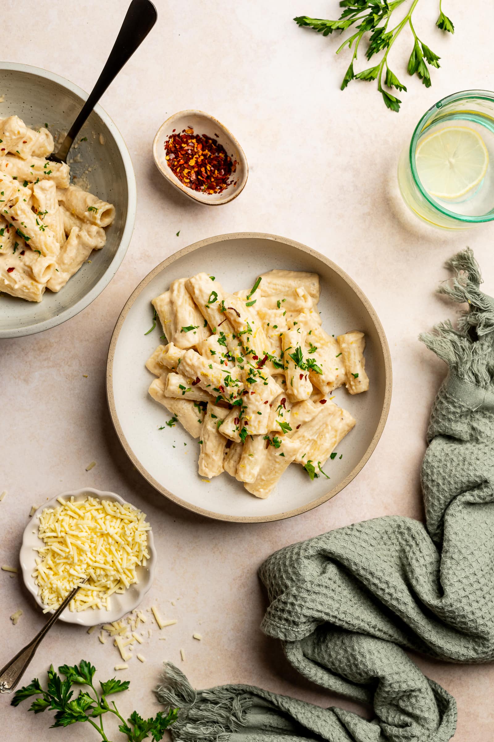 Cashew pasta garnished with red chili flakes, parsley, and lemon zest in a serving bowl.