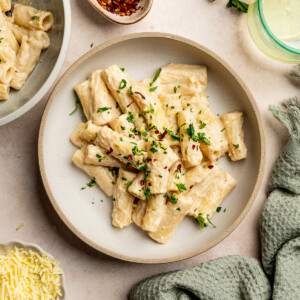 Cashew pasta garnished with red chili flakes, parsley, and lemon zest in a serving bowl.