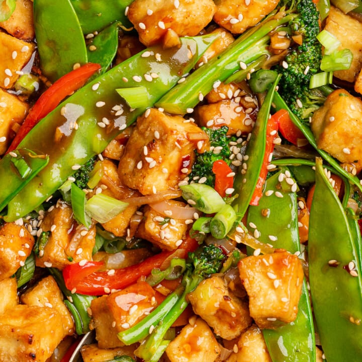 Tofu and vegetable stir fry garnished with sesame seeds and green onion.