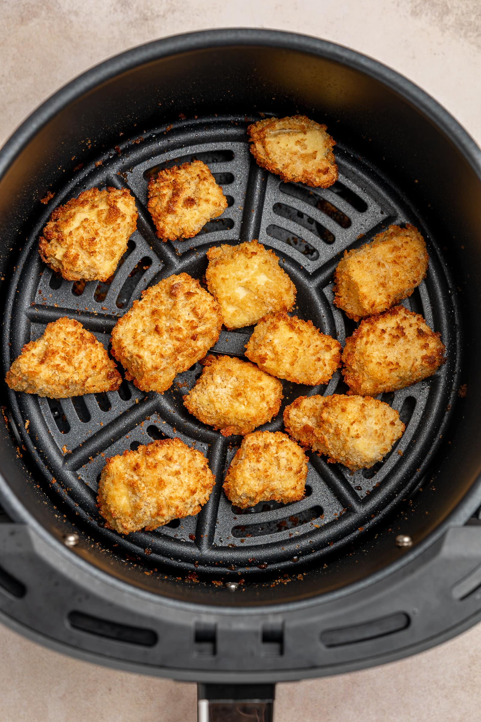 Crispy, golden tofu in an air fryer basket.