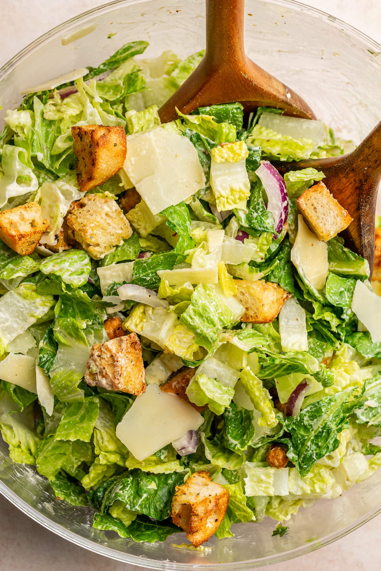 Dressing tossed into a bowl of caesar salad.