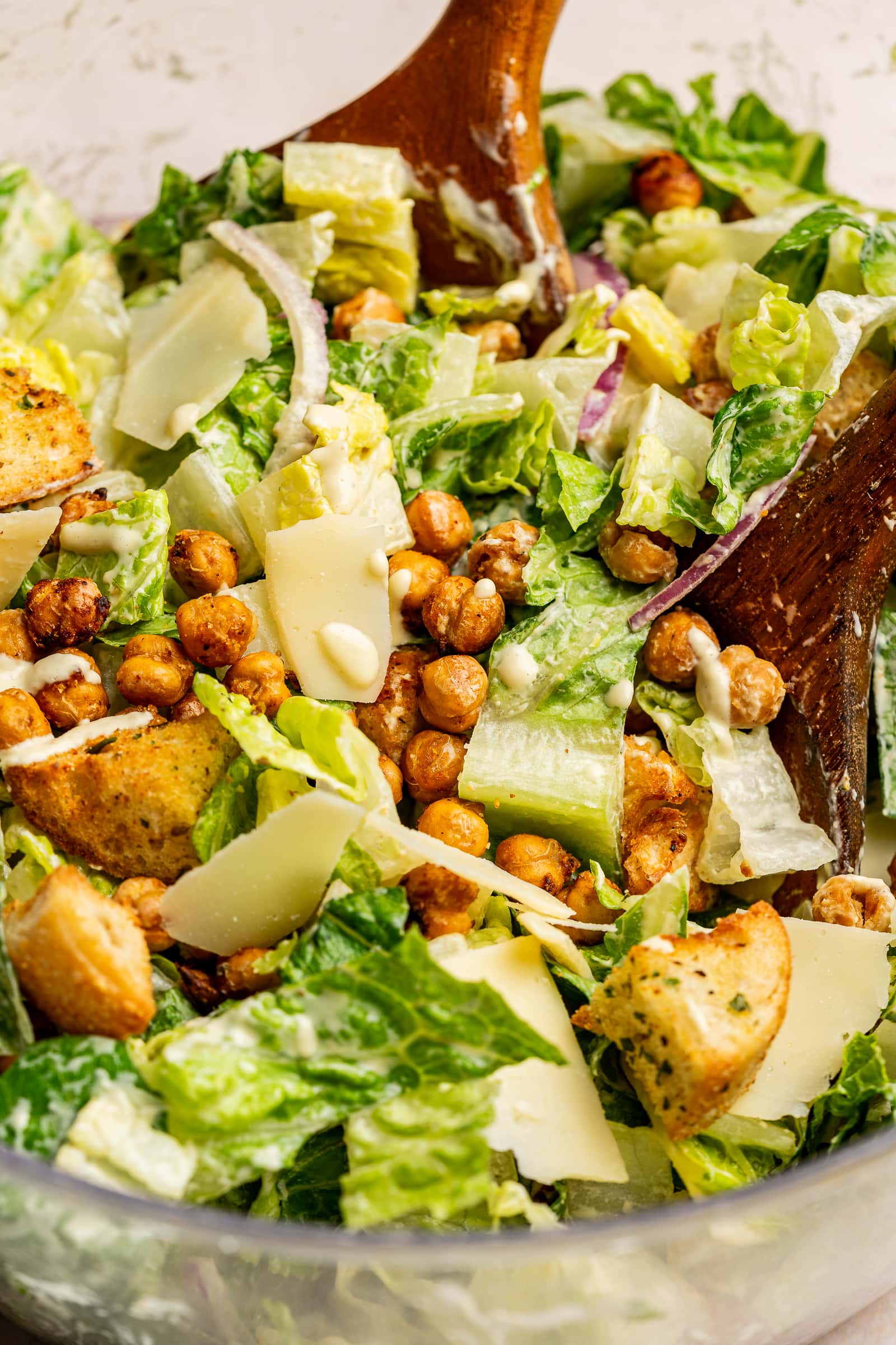 Caesar salad tossed in a bowl with chickpeas and croutons.